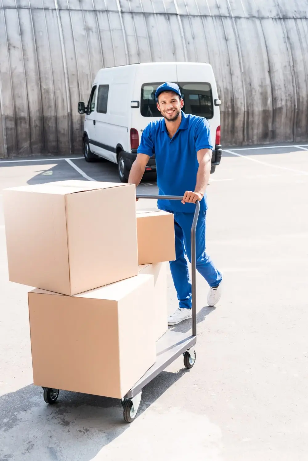 happy-delivery-man-with-cardboard-boxes-on-cart-e1618304324777